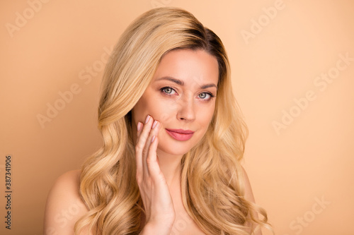 Photo of beautiful lady apply new anti age balm on perfect facial skin wear nothing isolated pastel beige background