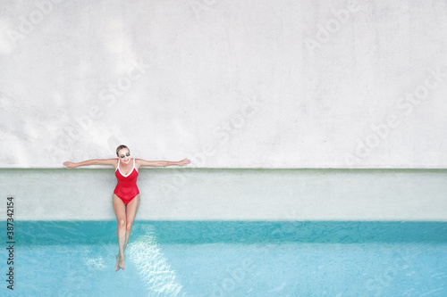 Enjoying suntan. Vacation concept. Top view of slim young woman in red swimsuit in the swimming pool. © luengo_ua
