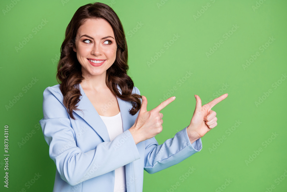Photo of cute lady curly hairstyle indicate look fingers empty space wear blue blazer isolated green color background Photo of cute lady curly hairstyle indicate look fingers empty space wear blue blazer isolated green color background