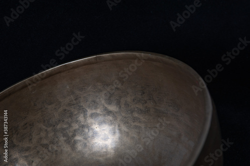 A jar of yellow handmade metal with traces of tools on a black background