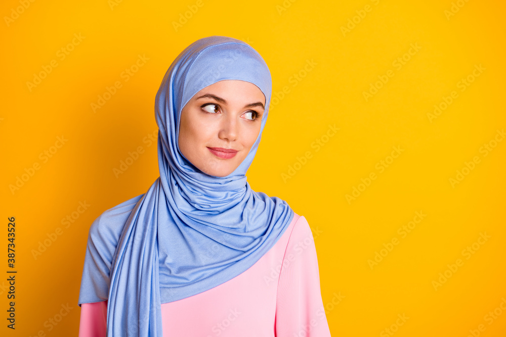 Close-up portrait of nice attractive cheery smart muslimah wearing hijab looking aside isolated over bright yellow color background Close-up portrait of nice attractive cheery smart muslimah wearing hijab looking aside isolated over bright yellow color background