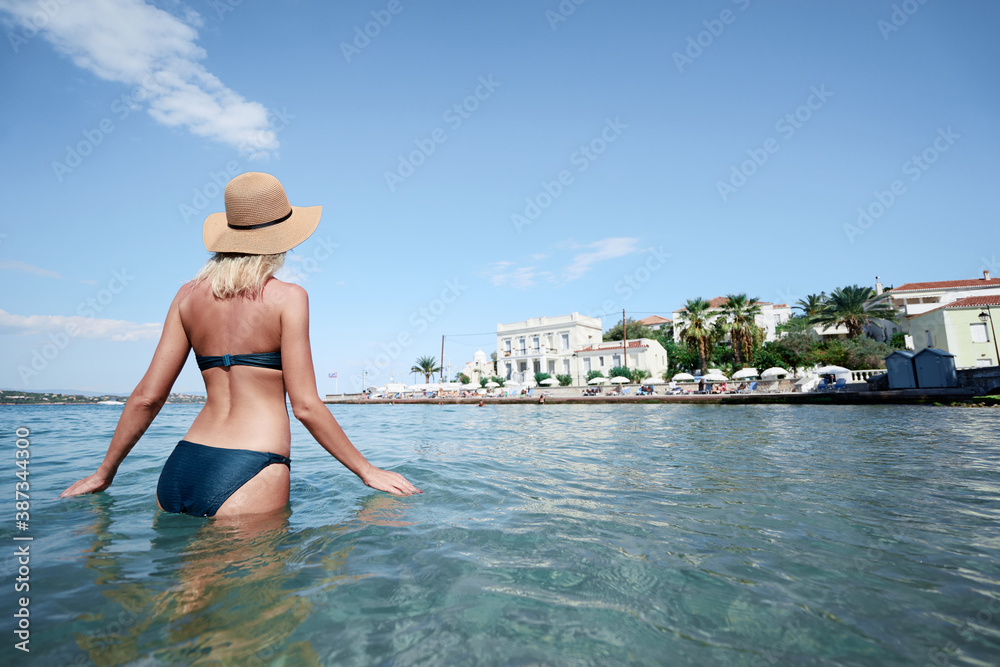 Vacation on the seashore. Back view of young woman enjoying the view of the Spetses Island, Greece.