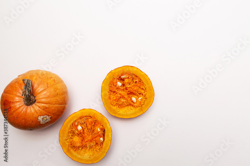 Pumpkins, whole and halves top view on a light pink background space for text.