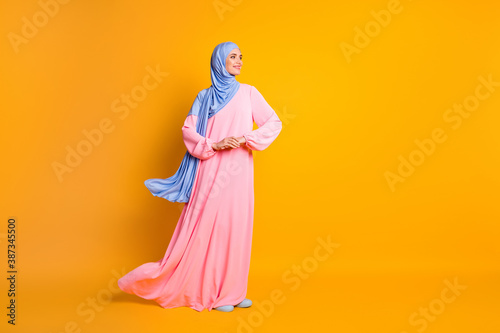 Full length body size view of pretty cheery feminine muslimah wearing hijab dress festal day isolated on bright yellow color background photo