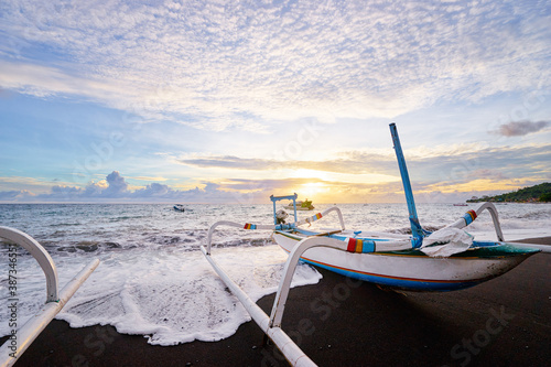 Beautiful sunrise. Ocean, beach and indonesian fishing boats. photo