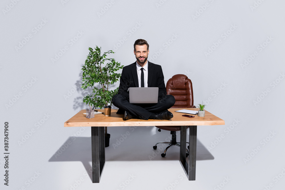 Full length photo of handsome business guy hold notebook knees good mood sitting table lotus yoga pose love his job wear blazer shirt pants shoes suit isolated grey background Full length photo of handsome business guy hold notebook knees good mood sitting table lotus yoga pose love his job wear blazer shirt pants shoes suit isolated grey background
