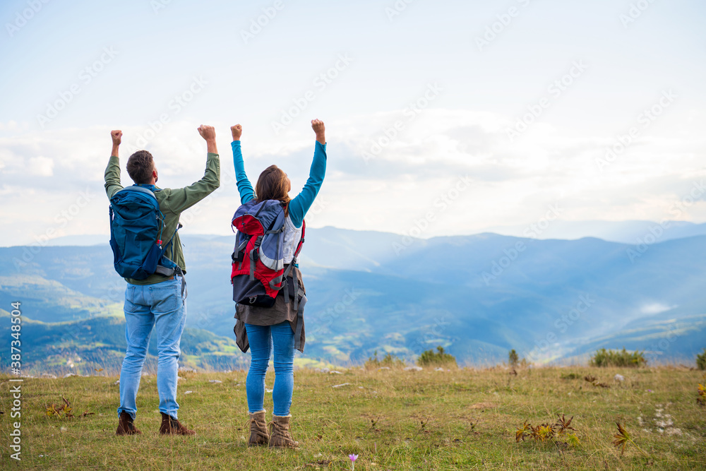 Happy travelers couple conquered top of mountain, raises hands up Happy travelers couple conquered top of mountain, raises hands up
