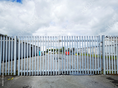 Security fence and gates outside a factory unit car park. The gates are closed and the factory is shut for the night.
