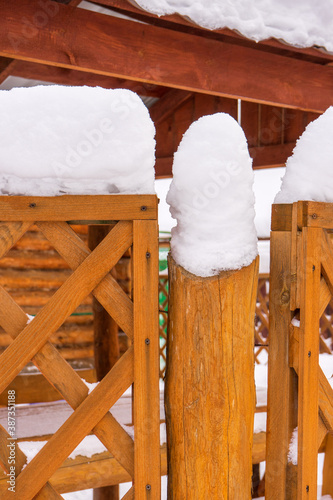 Wooden fence and roof covered with snow in winter cloudy day after snowfall. Winter season, cold weather concept. Beautiful winter background in rustic style, copy space photo