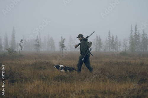 Cuadro en lienzo Hunter crossing foggy swamp with his dog