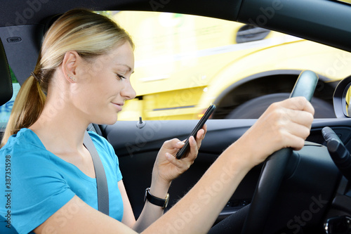Frau fährt mit Auto, bedient ein Smartphone und ist abgelenkt vom Straßenverkehr © Dan Race
