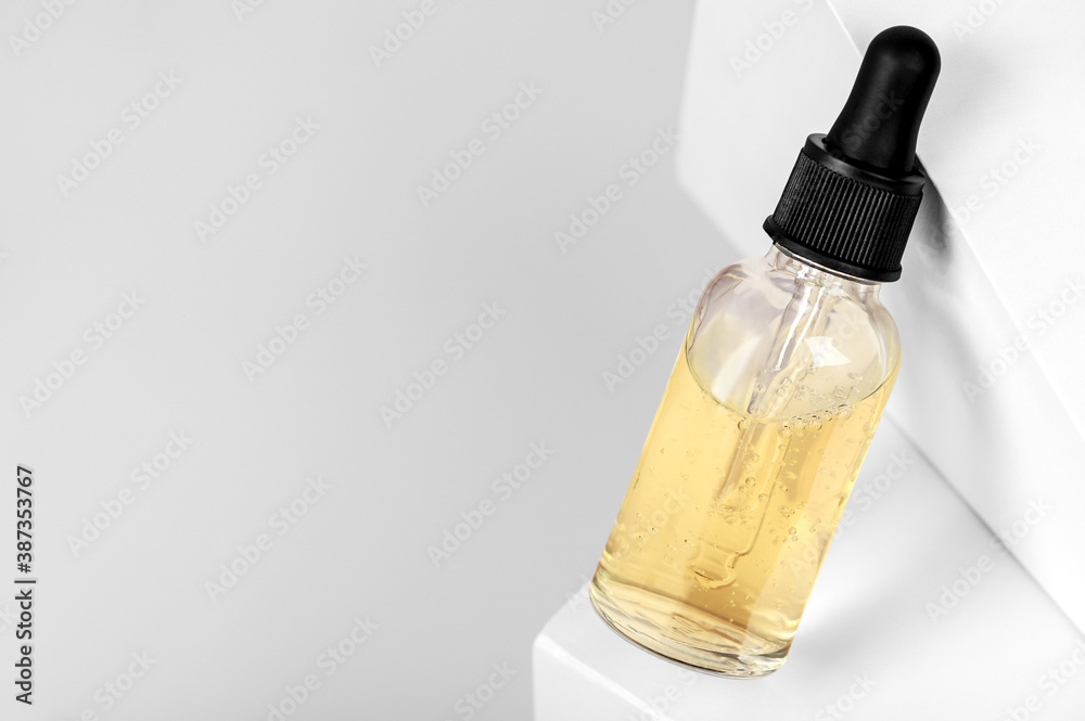 Serum in a transparent bottle with a pipette on a geometric white background. Cosmetic moisturizer with retinol in a glass container. Natural beauty organic moisturizing oil. Copy space.