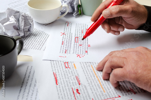 Lorem ipsum text.Process of proofreading.Man checking the text.Cups, documents abd man holding red marker photo