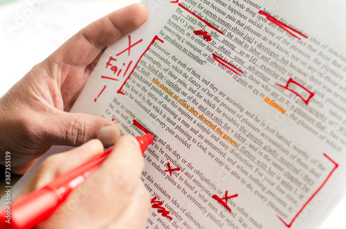 Man holding red marker and proofreading the story.Closeup of document and red marks on it photo