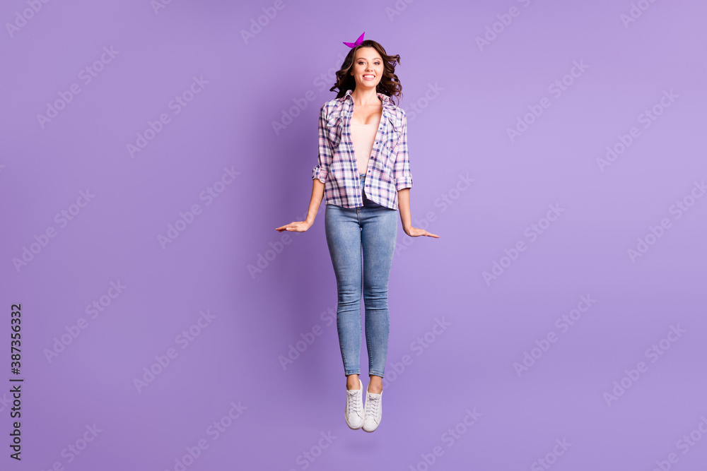 Full length photo of charming pretty brown hair girl wear checkered shirt jumping high isolated violet color background Full length photo of charming pretty brown hair girl wear checkered shirt jumping high isolated violet color background