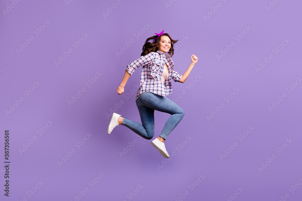 Profile photo of charming shiny woman wear vintage checkered shirt denim jeans jumping high isolated violet color background