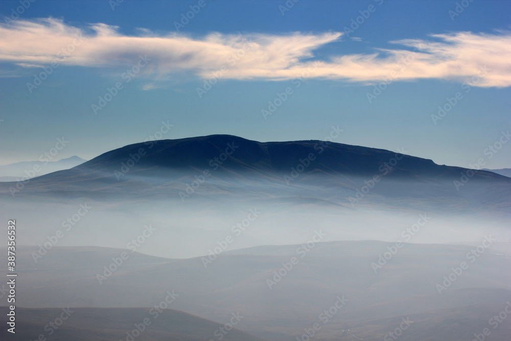 Foggy mountain landscape and blue sky.