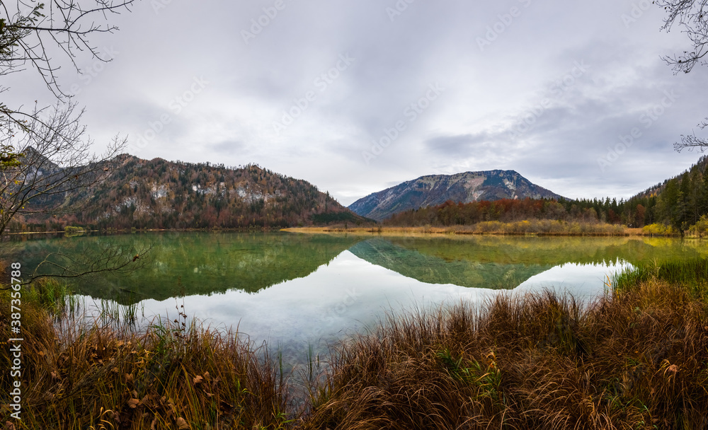 mountains and lake with beautiful reflection with grass on the shore panorama