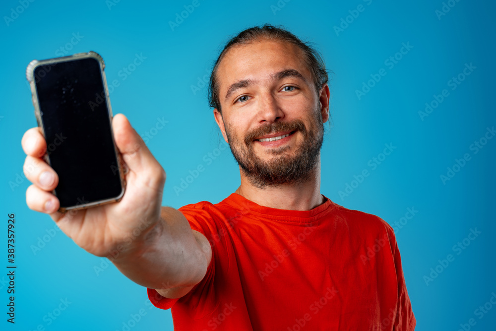 Smiling bearded man showing you black smartphone screen Smiling bearded man showing you black smartphone screen