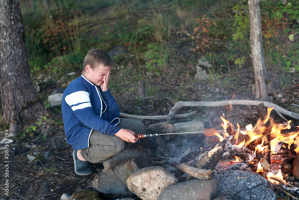 Boy frying bread over fire in forest Boy frying bread over fire in forest