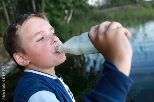 Boy drinking milk from bottle by lake