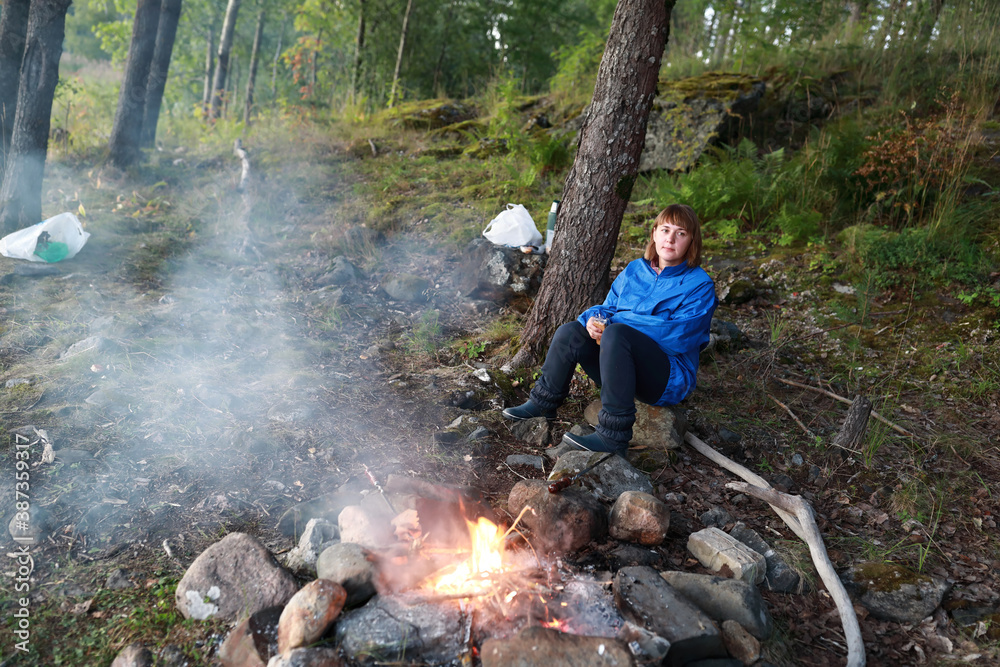 Woman by fire in forest in evening Woman by fire in forest in evening