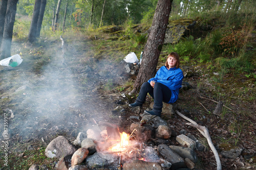 Woman by fire in forest in evening