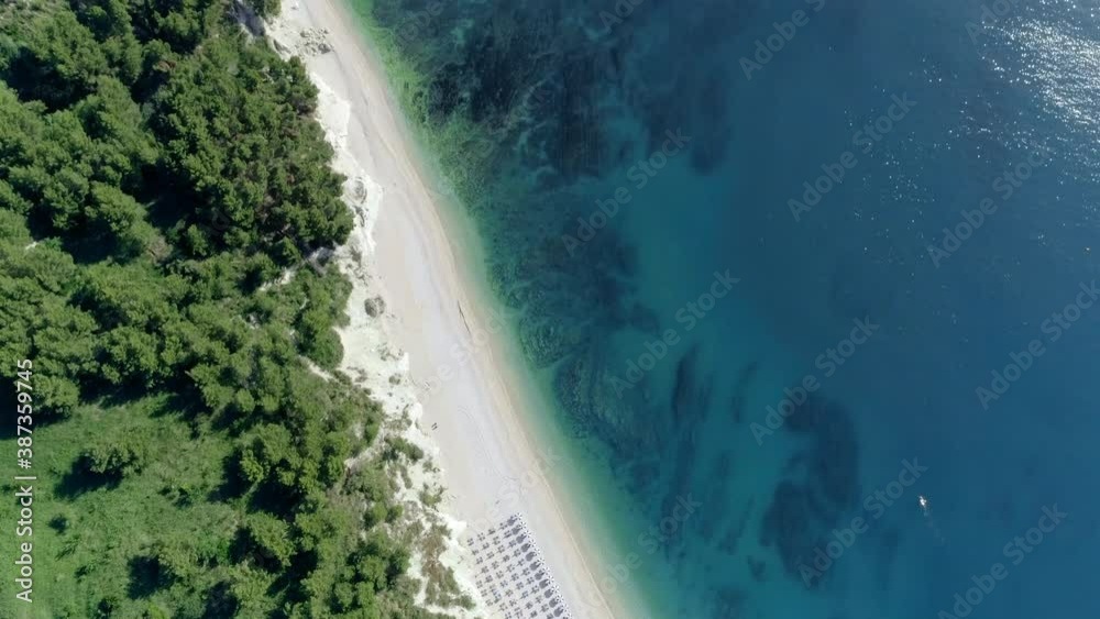 Aerial zenithal view of the San Michele beach near Sirolo, Conero mountain Marche (Italy) in the summer season.The sandy beach with umbrellas and sunbeds divides the steep cliff from the blue sea.