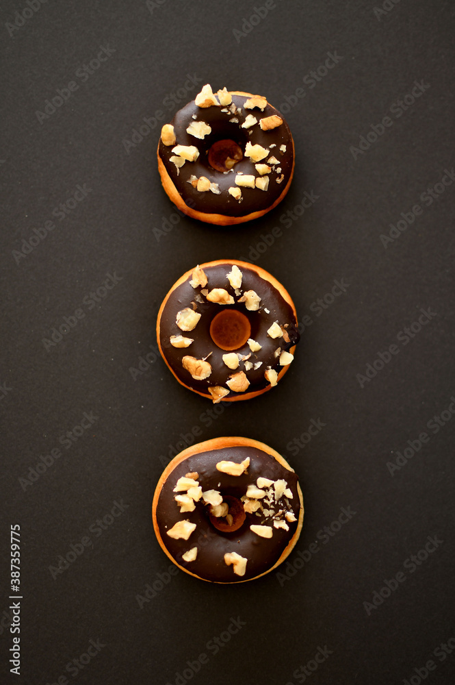 Fototapeta premium Delicious chocolate donuts isolated on a black background.