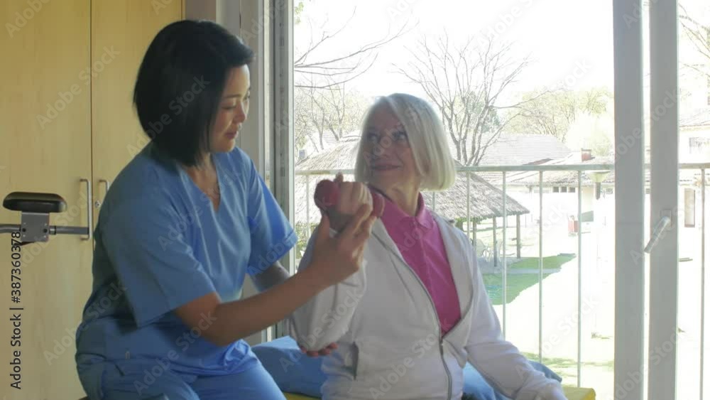 Asian female doctor helping elderly woman in hospital moving her arm. Slow motion Asian female doctor helping elderly woman in hospital moving her arm. Slow motion