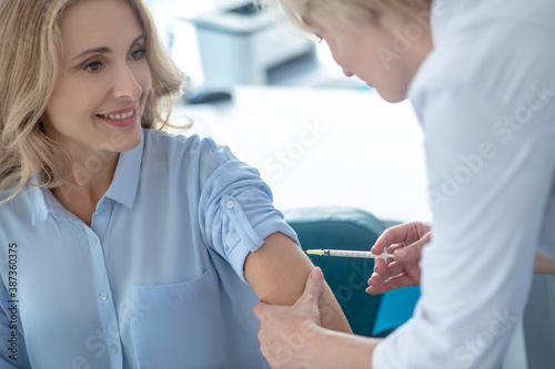 Female doctor making injection into arm of blonde female patient