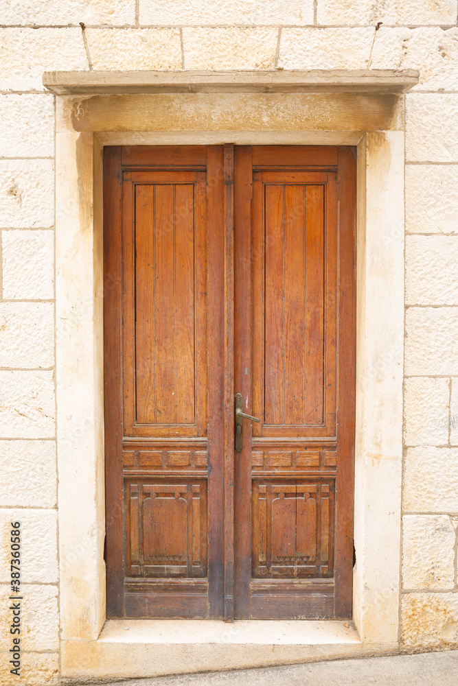 Vintage brown window with shutters on stone wall.