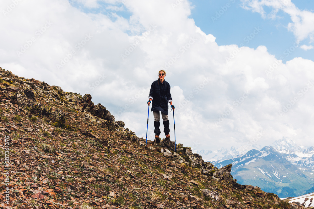 A young female tourist stands on top of a mountain