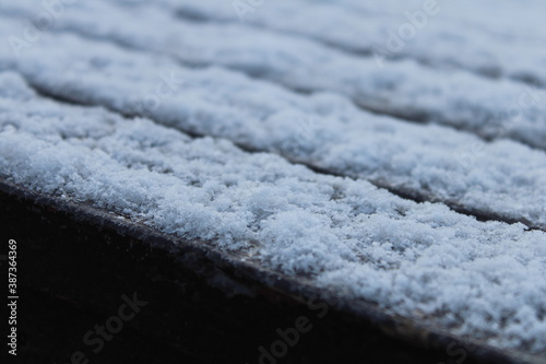 The first snow on a city bench in autumn.