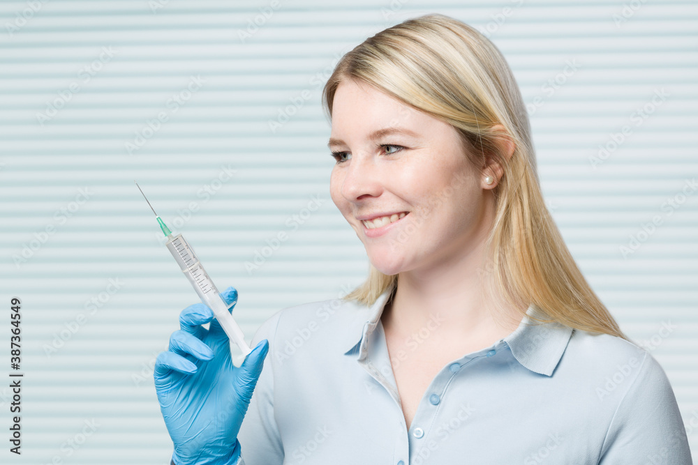 young doctor or nurse with a syringe filled up with a vaccine in her hand young doctor or nurse with a syringe filled up with a vaccine in her hand
