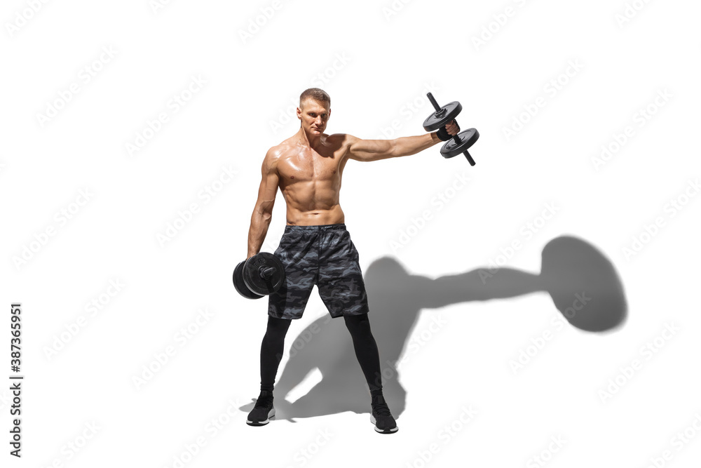 Dumbbells and weights. Stylish young male athlete on white studio background, portrait with shadows. Sportive fit model in motion and action. Body building, healthy lifestyle, style concept. Dumbbells and weights. Stylish young male athlete on white studio background, portrait with shadows. Sportive fit model in motion and action. Body building, healthy lifestyle, style concept.