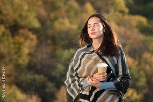 Beautiful girl on nature background of dreams. Travel in the fall. Coffee in hand.