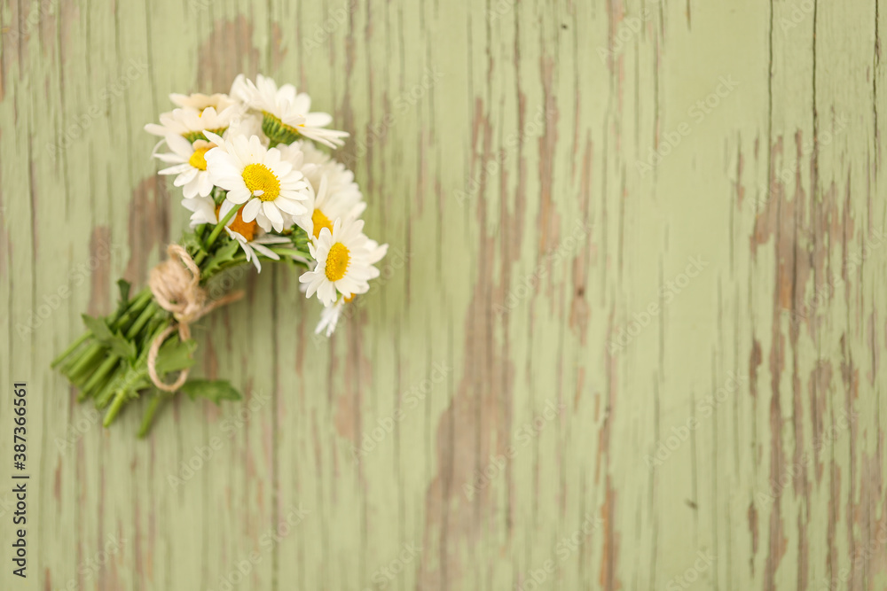 Fototapeta premium Small bunch of chrysanthemum flowers tied with brown string on painted green background with copy space. Horizorntal flat lay image.