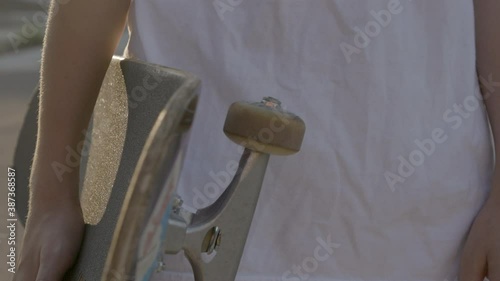 Closeup on a skateboard held by a skater at his side. photo