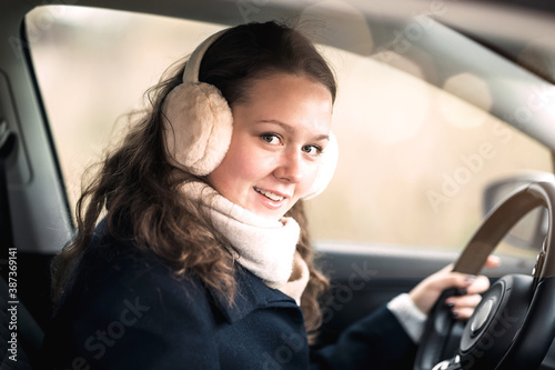 Happy young woman dressed in stylish clothes in a car.