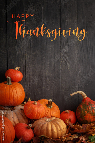 Thanksgiving Greetings. Pumpkins and dry leaves on a dark wooden background.