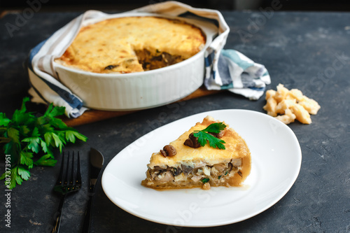 Traditional French pie with custard, chicken, porcini mushrooms and country cheese. On a dark table. Top view, side view.