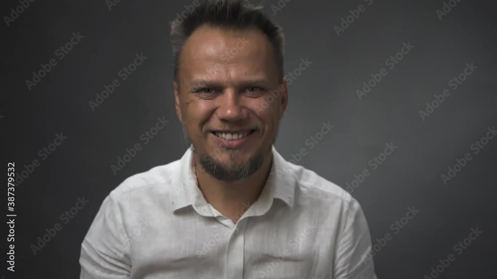 Middle-aged man with a beard smiles at the camera in the studio. Man smiles approvingly. High quality FullHD footage. Middle-aged man with a beard smiles at the camera in the studio. Man smiles approvingly. High quality FullHD footage.