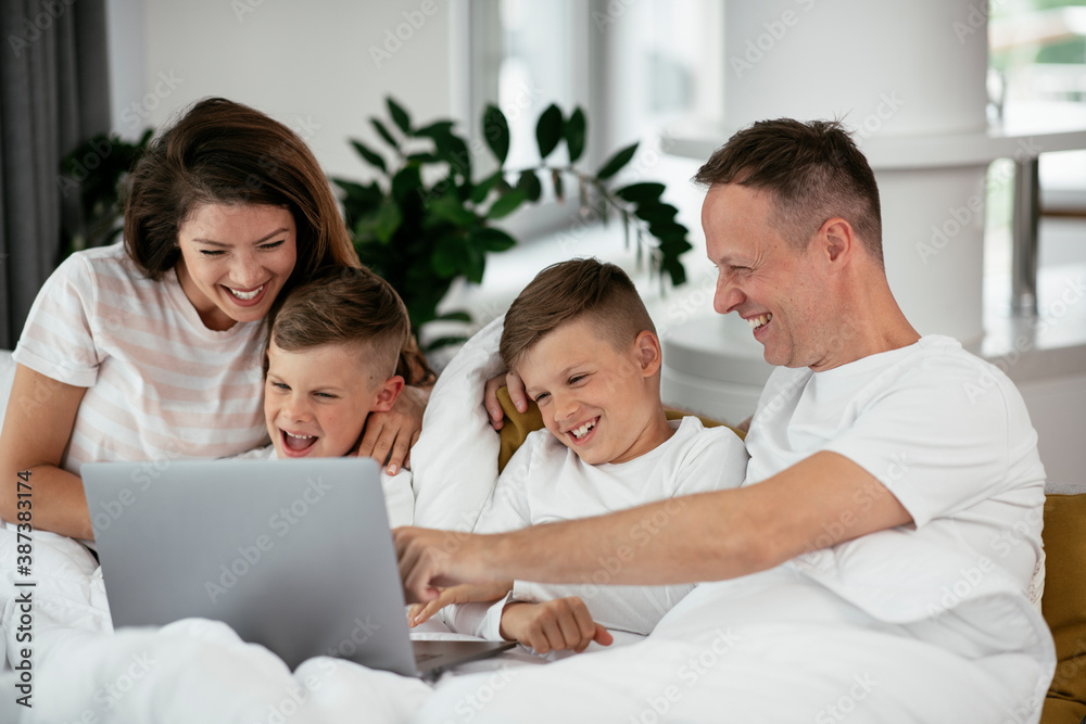 Beautiful parents with kids enjoying at home. Young family watching movie on lap top. Beautiful parents with kids enjoying at home. Young family watching movie on lap top.