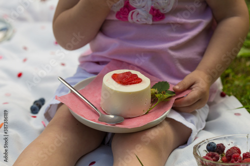 girl eating cake on family picnic by summer. Child holding  mini cake