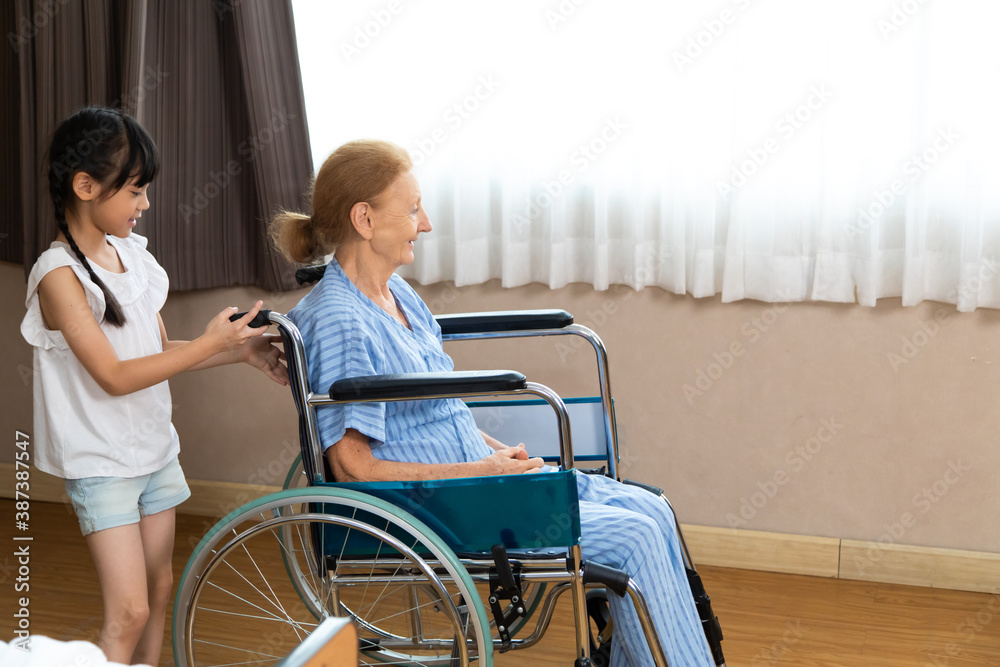 Happy senior patient sitting in wheelchair with grandchild. grandmother and granddaughter enjoying talking together. Happy senior patient sitting in wheelchair with grandchild. grandmother and granddaughter enjoying talking together.