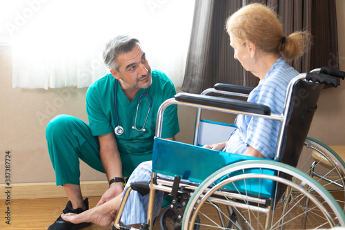 Orthopedic doctor examining senior woman knee in hospital. Doctor checking elderly woman patients knee