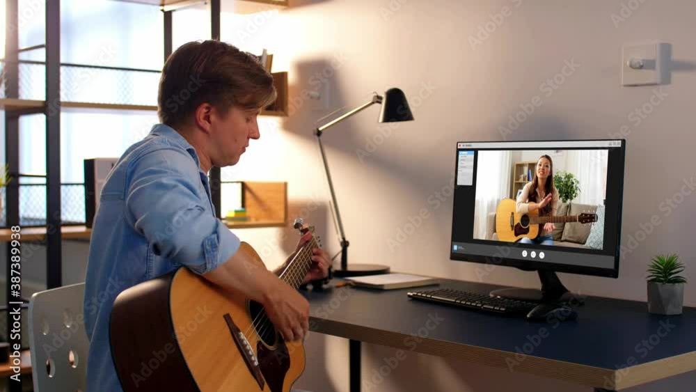 music, e-learning and technology concept - young man or musician with computer learning to play guitar with teacher online at home