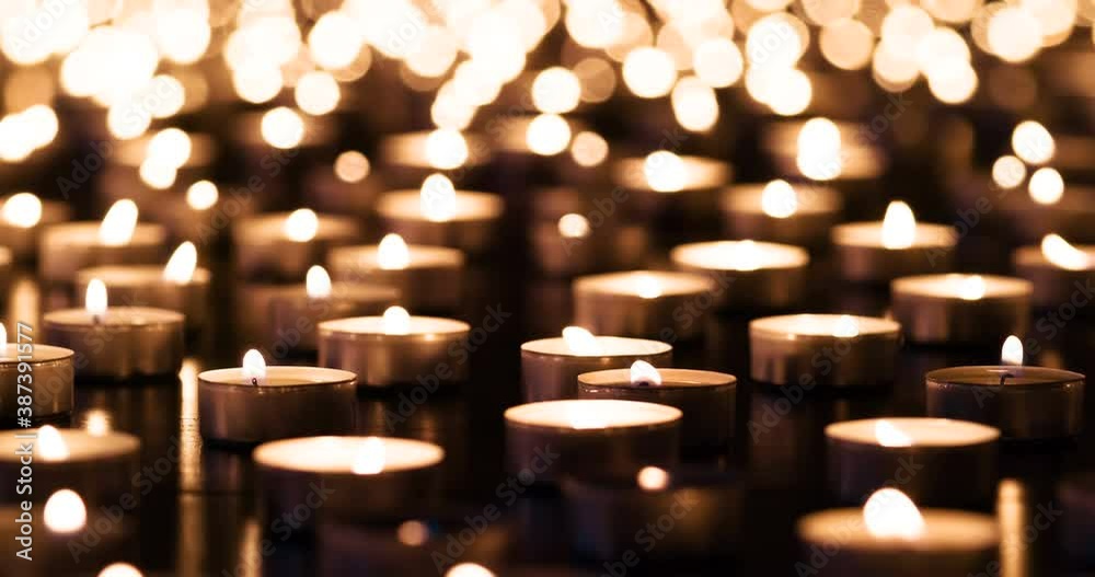 Candles in Memory of the Event. A large field of lit small candles on a dark granite surface. The air is slowly waving lights. Filmed at a speed of 120fps
