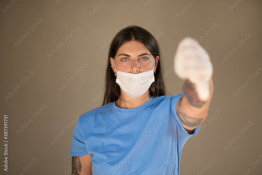 Doctor wearing a face mask passing a medical glove to a person